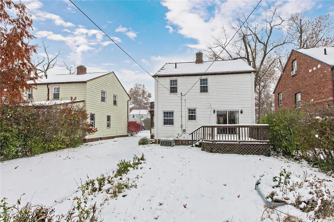 Snow covered property with a wooden deck and a chimney