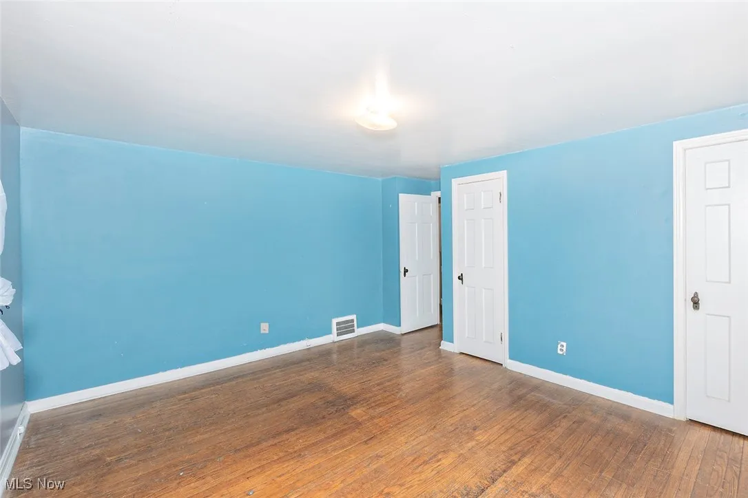 Unfurnished bedroom with dark wood-style flooring and baseboards