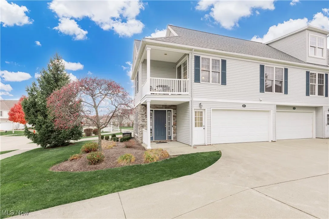 Traditional-style home with a garage, driveway, a front yard, a balcony, and a shingled roof