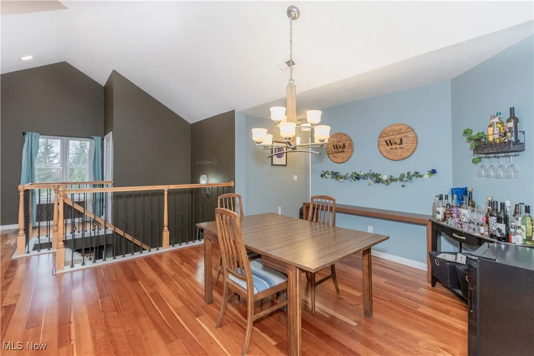 Dining space with light wood-type flooring, vaulted ceiling, and a chandelier