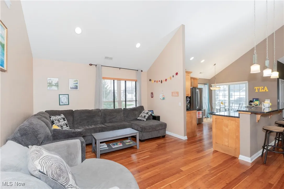 Living room featuring healthy amount of natural light, light wood-style flooring, high vaulted ceiling, and recessed lighting
