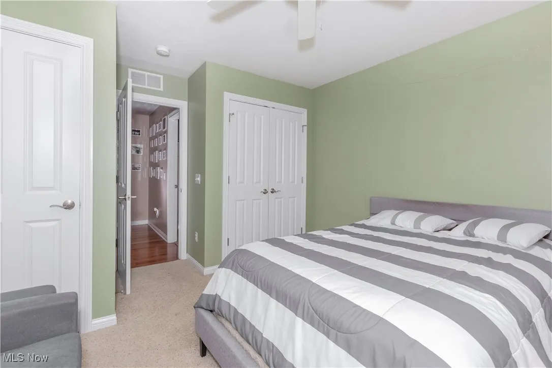 Bedroom with a closet, ceiling fan, and light colored carpet