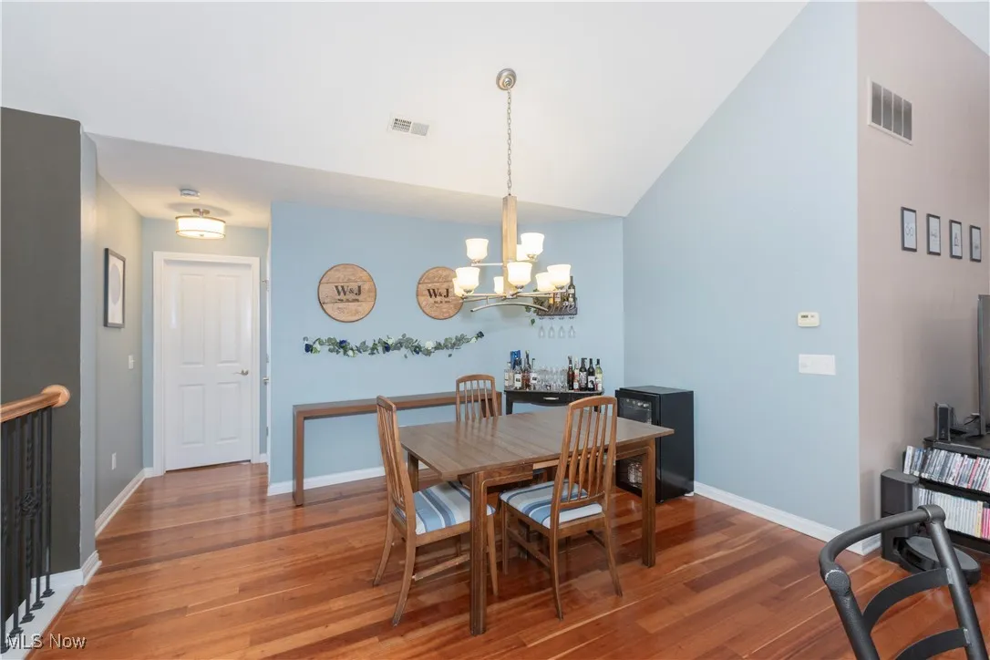 Dining area featuring wood finished floors, a chandelier, and lofted ceiling