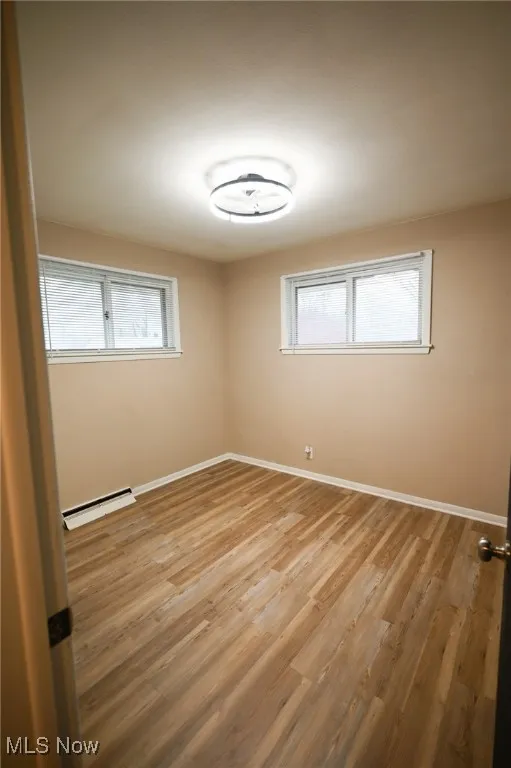 Unfurnished room featuring light wood-style floors and a baseboard heating unit