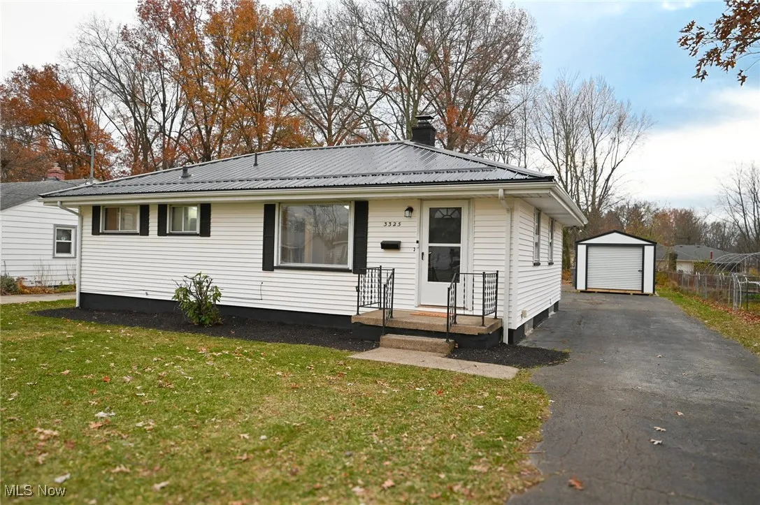 View of front of property featuring an outbuilding, driveway, a front lawn, a garage, and a chimney
