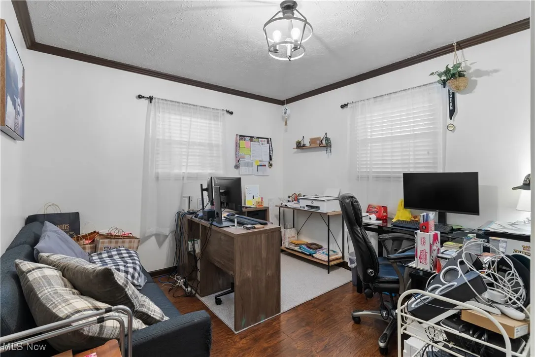 Office space with wood finished floors, ornamental molding, and a textured ceiling