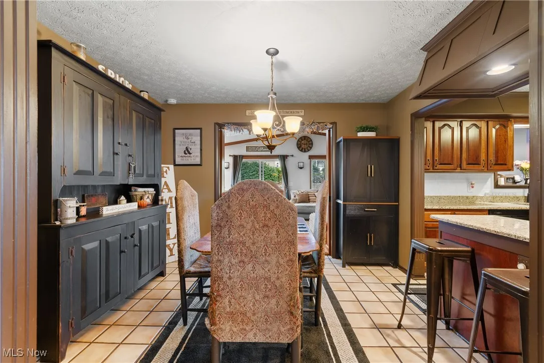 Dining area featuring a textured ceiling, light tile patterned flooring, and a chandelier