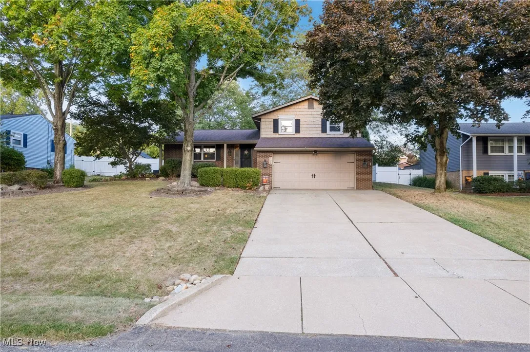 Tri-level home featuring driveway, brick siding, and a garage