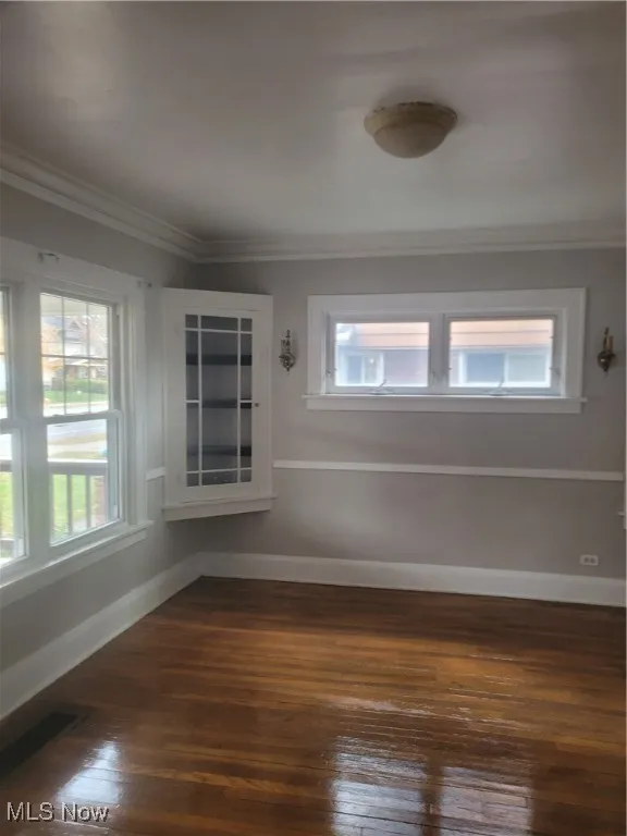 Spare room with dark wood-type flooring and crown molding