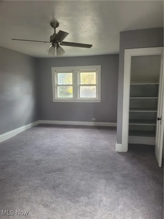 Unfurnished bedroom featuring carpet flooring, a closet, and a ceiling fan