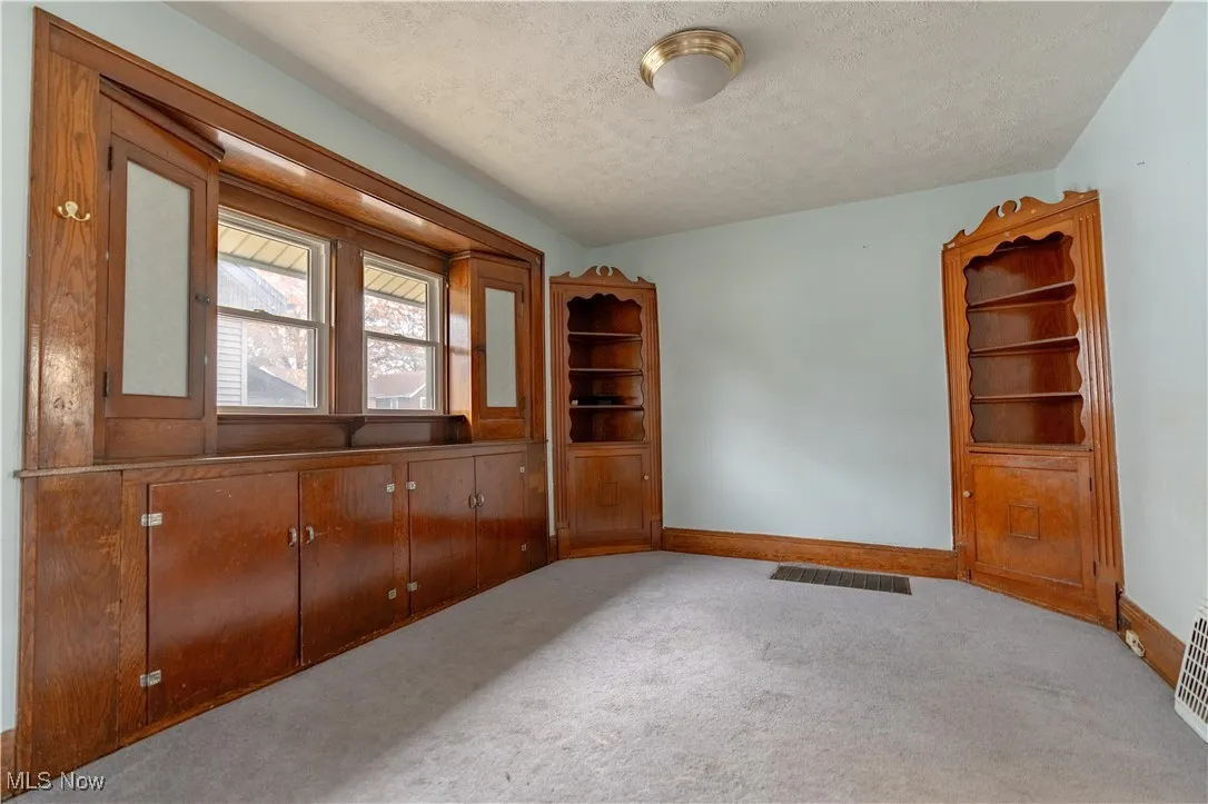 Carpeted spare room with a textured ceiling and baseboards