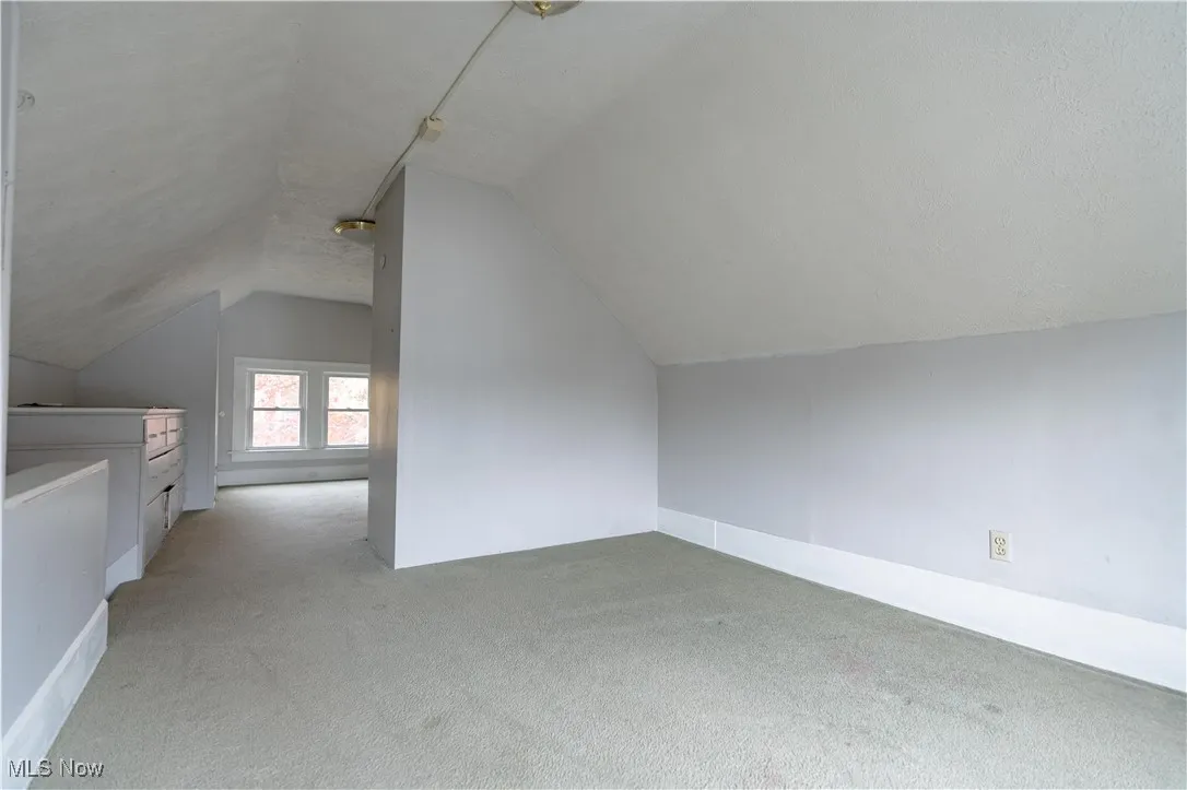 Bonus room with light colored carpet and lofted ceiling