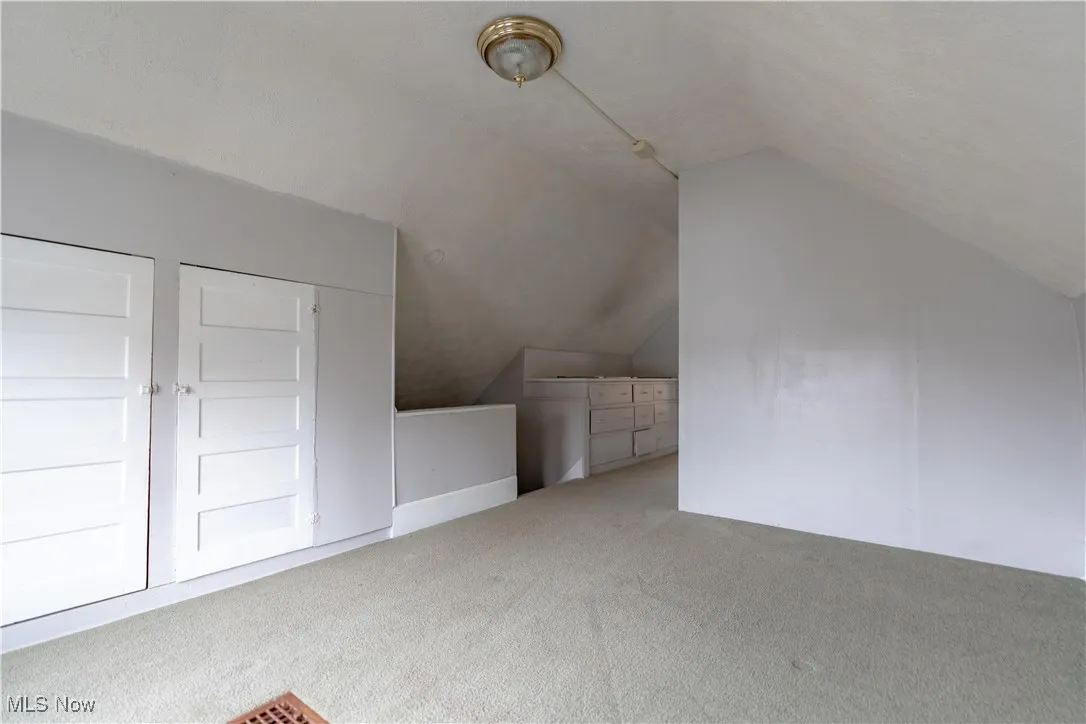 Additional living space featuring vaulted ceiling and carpet flooring