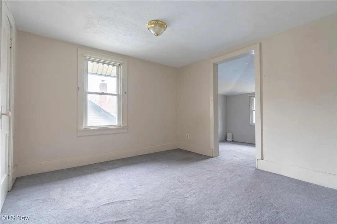 Carpeted empty room with healthy amount of natural light and a textured ceiling