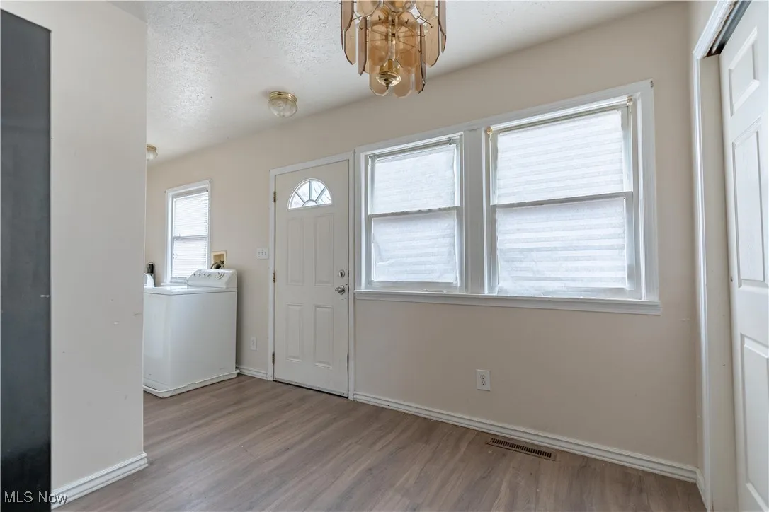Entryway featuring washer / clothes dryer, light wood-type flooring, and a textured ceiling