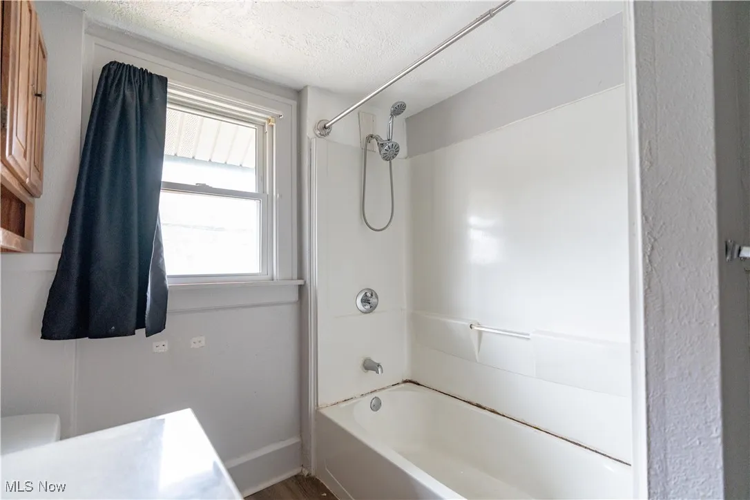 Bathroom featuring  shower combination, vanity, and a textured ceiling