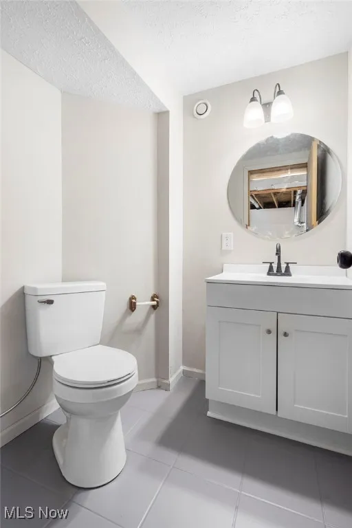 Bathroom featuring a textured ceiling, light tile patterned floors, and vanity