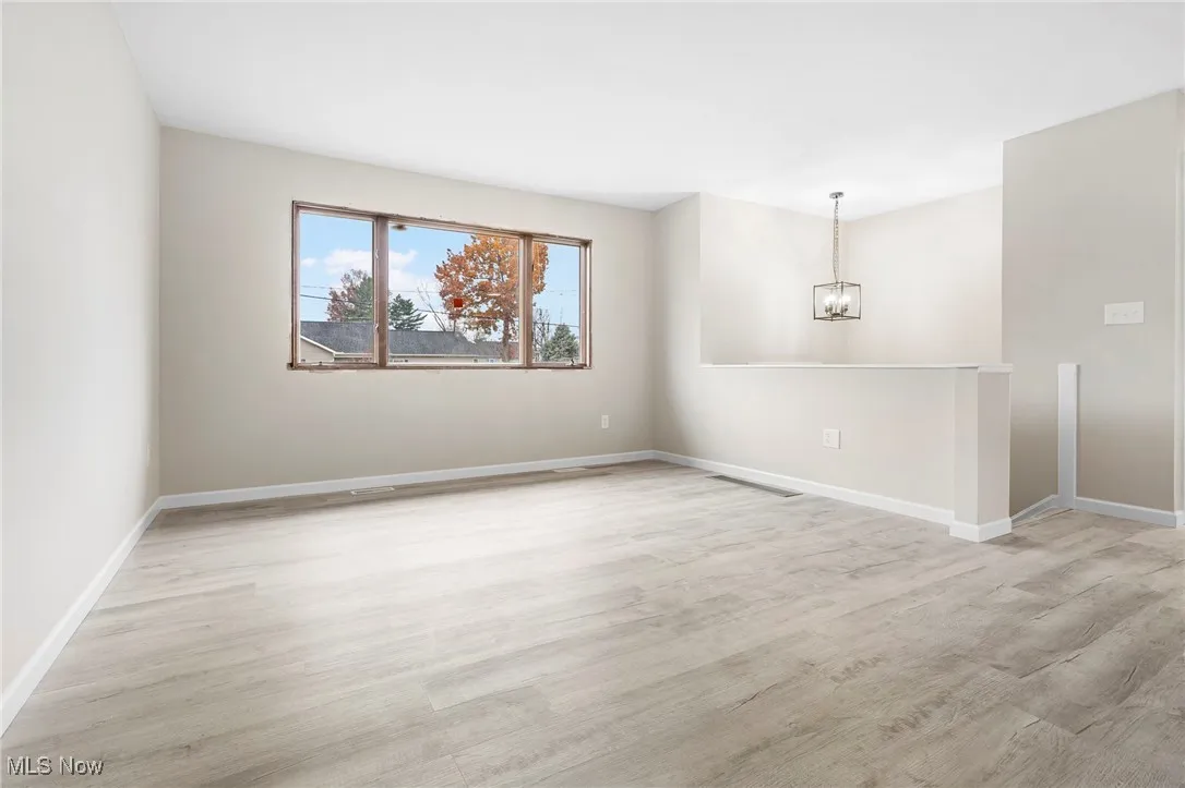 Empty room featuring light wood finished floors and a chandelier