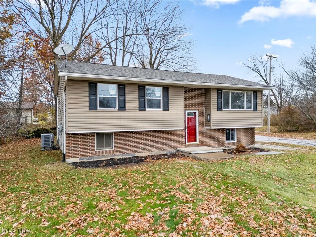 Split foyer home featuring a front lawn, brick siding, and a shingled roof