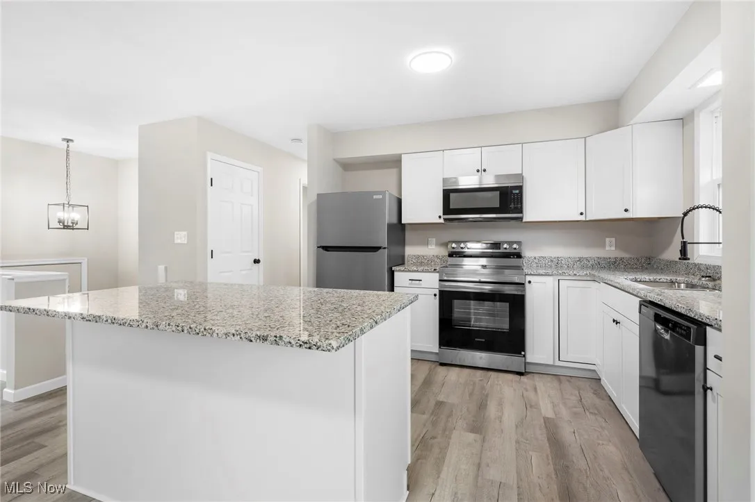 Kitchen featuring appliances with stainless steel finishes, a center island, white cabinets, and light wood-type flooring