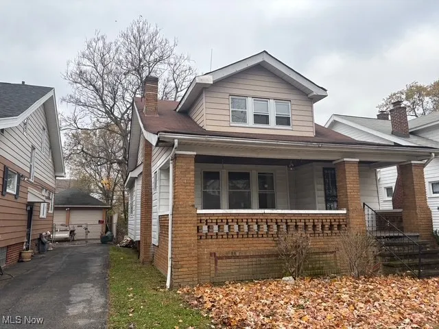 Bungalow-style house with brick siding, a porch, and a detached garage