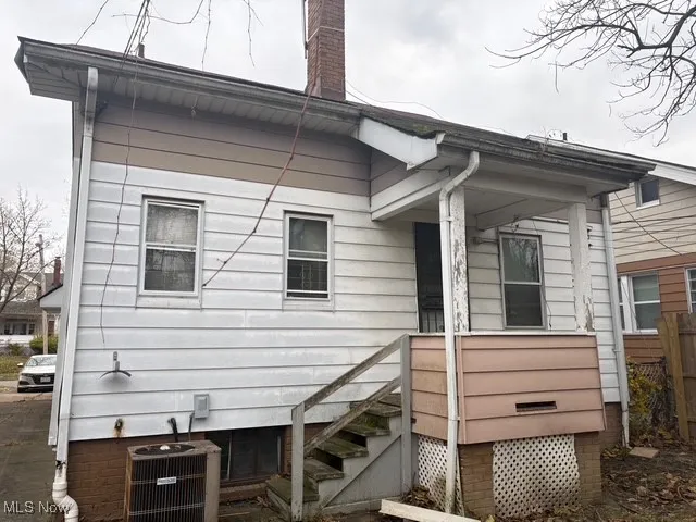 View of side of home with a cooling unit and a chimney