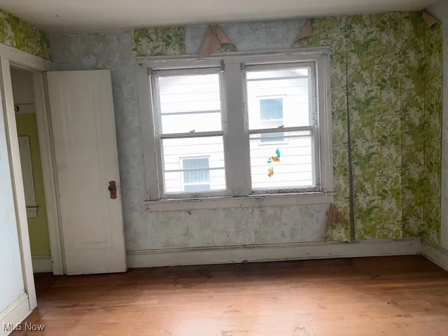Spare room featuring wallpapered walls, light wood-style floors, and plenty of natural light