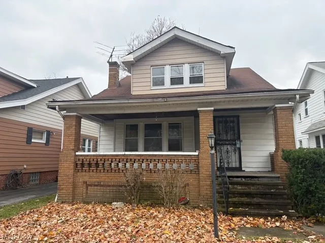 Bungalow-style home featuring covered porch, a chimney, and brick siding