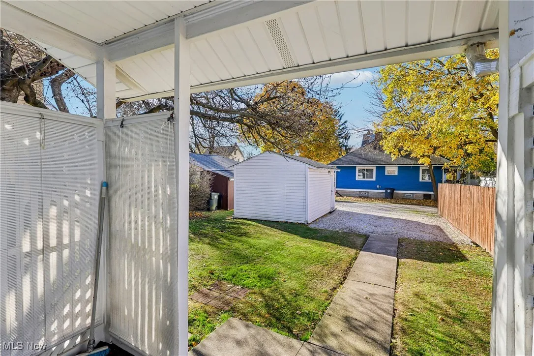 Look out from back door entrance showing a back yard, 1 car detached garage and driveway parking