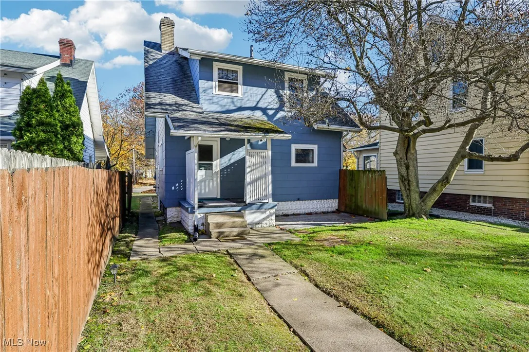 Rear view of property featuring small porch, patio, wood fencing, and a back yard
