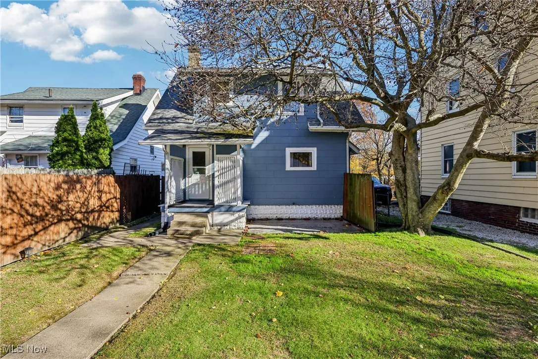 Rear view of the property with small back porch, patio, wood fencing and back yard