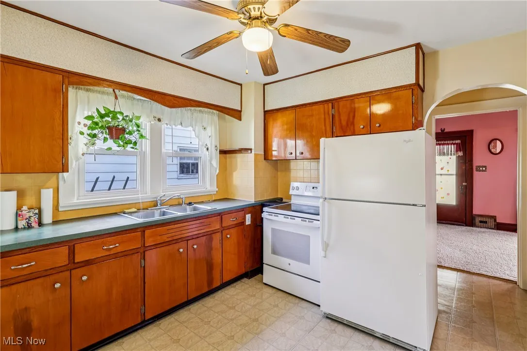 Kitchen with sink, cabinets, stove, refrigerator, ceiling fan / light and linoleum flooring