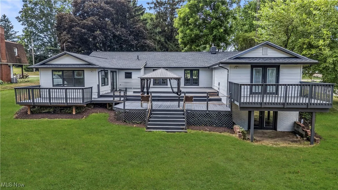 Rear view of house featuring a lawn, a wooden deck, french doors, a shingled roof, and a gazebo