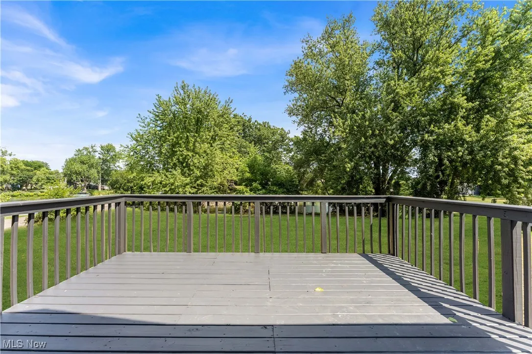 Wooden deck with a lawn and view of scattered trees