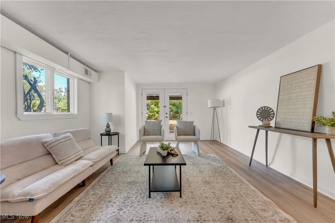 Living area featuring light wood finished floors, french doors, and a textured ceiling