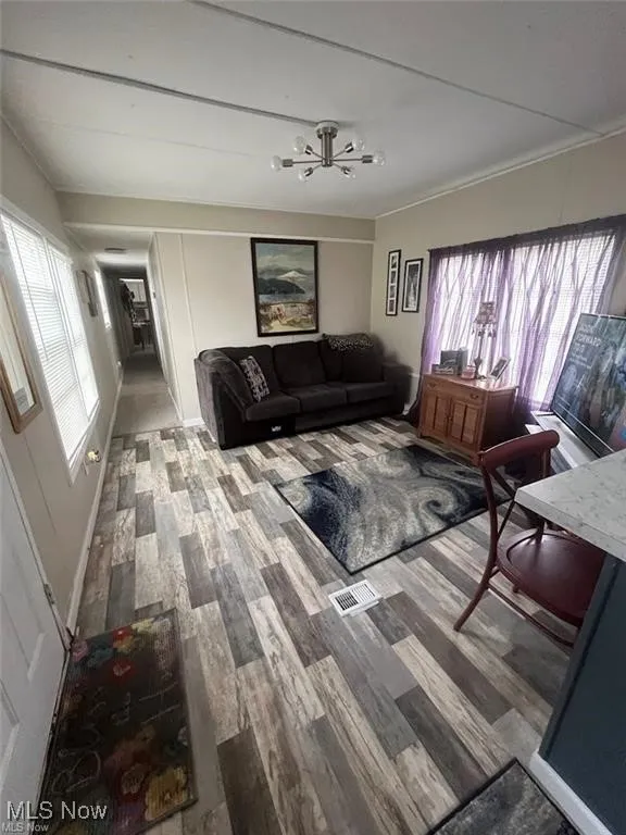 Living room with wood finished floors,
healthy amount of natural light, and a
chandelier