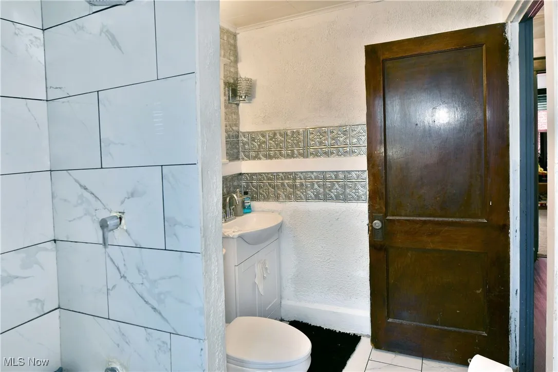Full bathroom featuring a textured wall, vanity, tile patterned floors, and crown molding