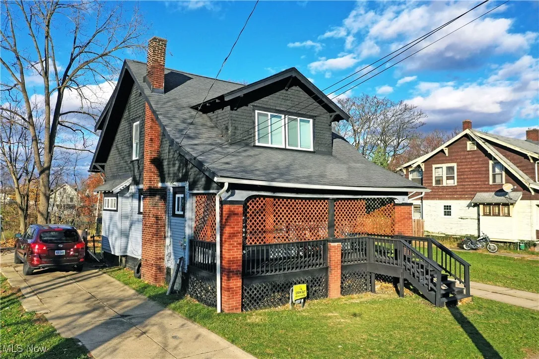 Rear view of property with a lawn, roof with shingles, a chimney, brick siding, and a porch