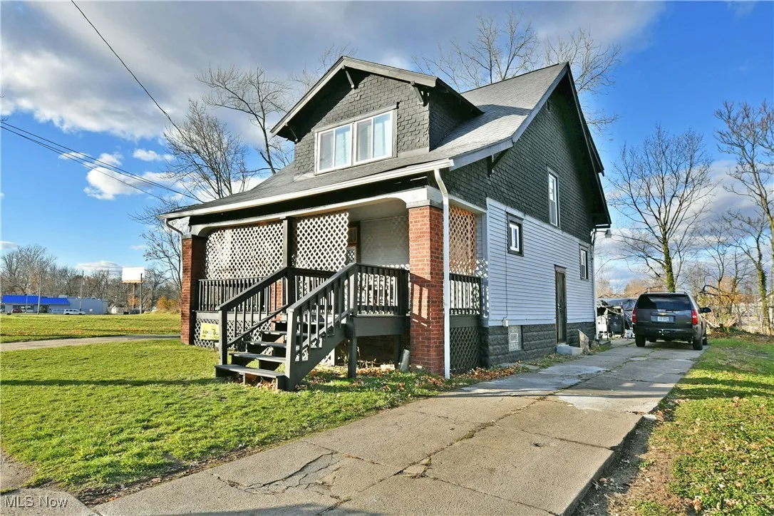 View of front of home with a front lawn, a porch, concrete driveway, roof with shingles, and stairway