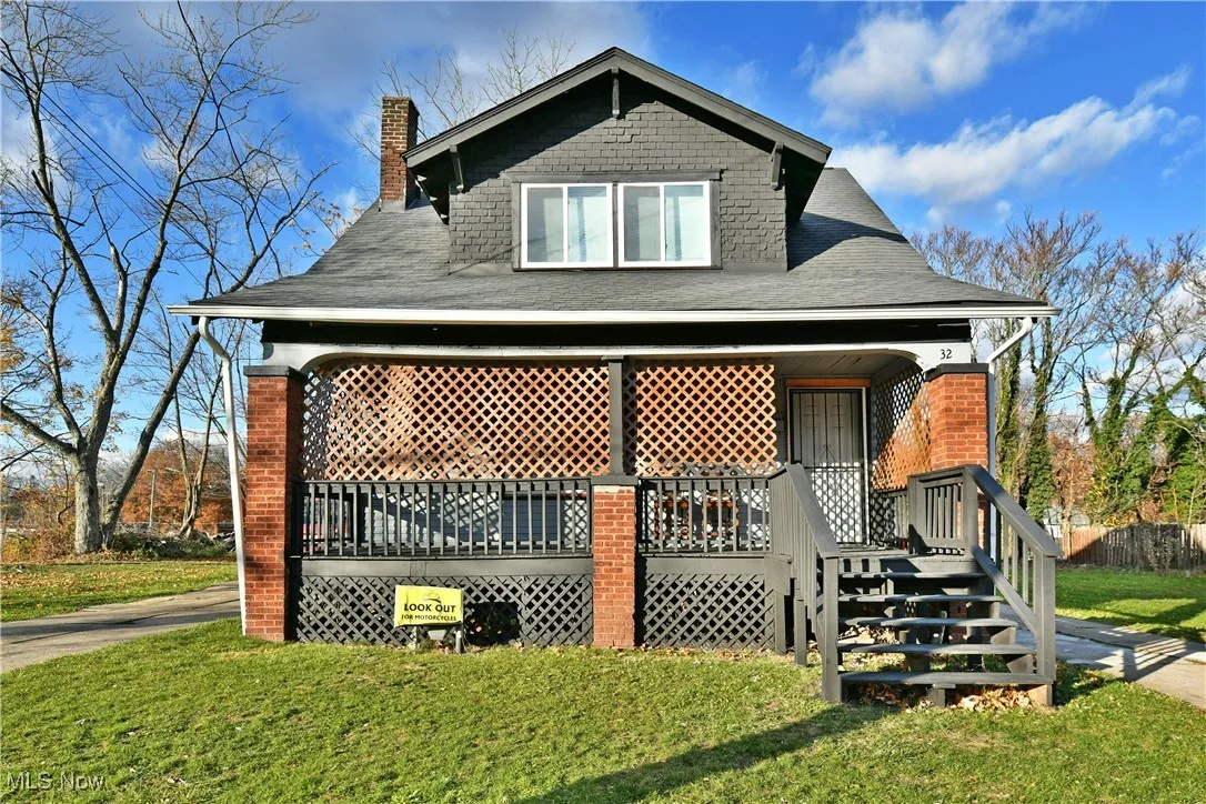 Rear view of house with covered porch, a lawn, a chimney, and a shingled roof