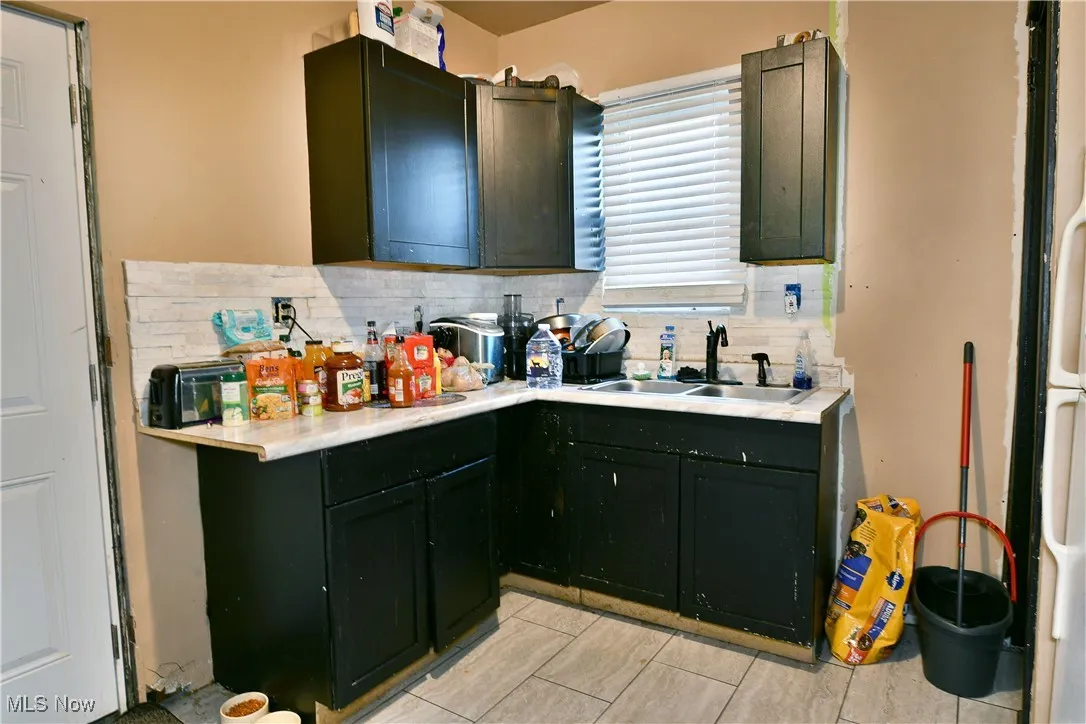 Kitchen with light countertops, decorative backsplash, and green cabinets