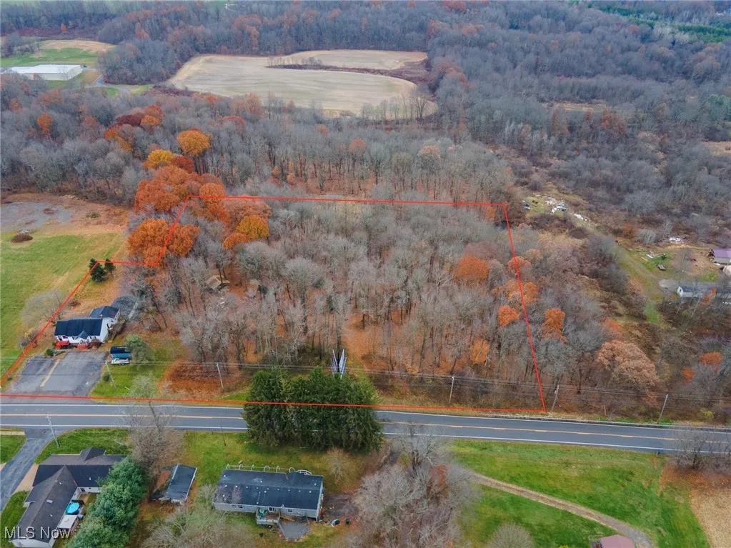 Aerial view of property and surrounding area featuring a heavily wooded area and property parcel outlined