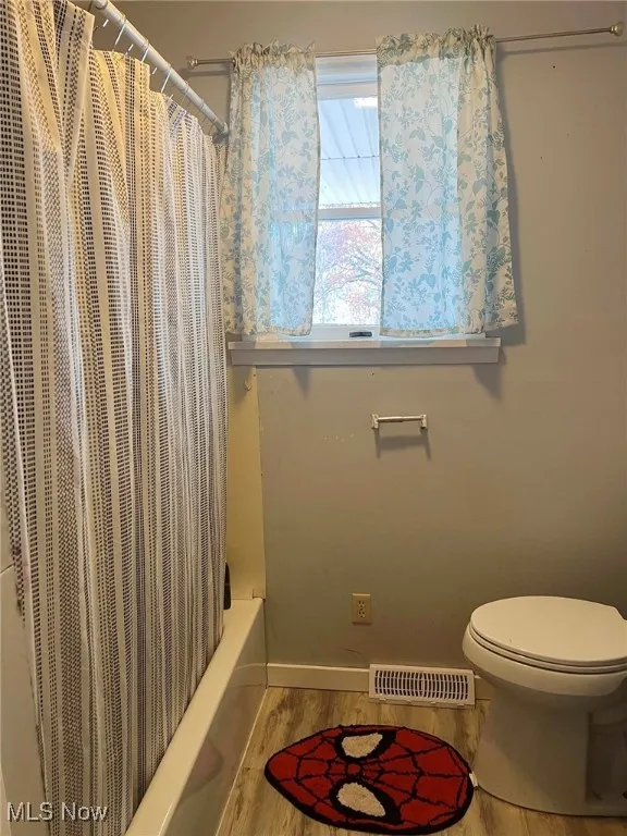 Bathroom featuring wood finished floors and shower / bath combo
