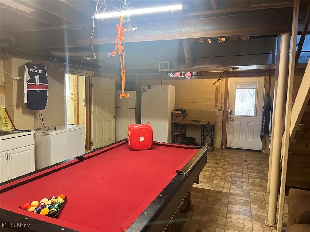 Recreation room featuring billiards, concrete block wall, and brick patterned flooring