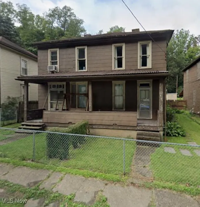 View of front facade featuring covered porch and a fenced front yard