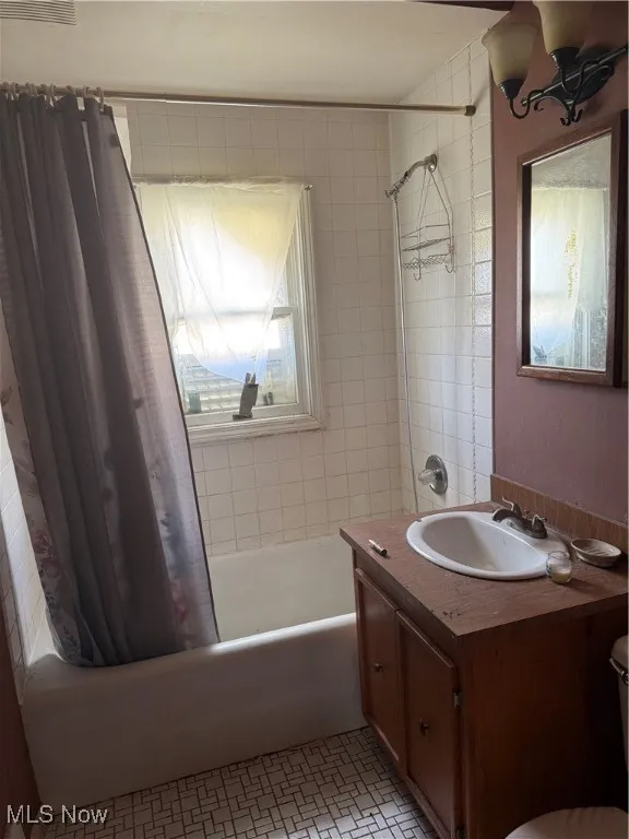 Bathroom with shower / tub combo, vanity, and light tile patterned floors