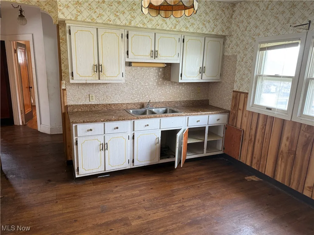 Kitchen with dark countertops, dark wood-style flooring, and wallpapered walls