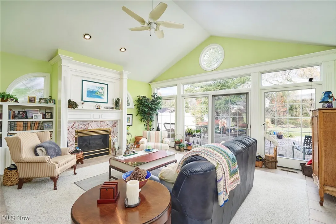 Living area with a premium fireplace, high vaulted ceiling, recessed lighting, and a ceiling fan