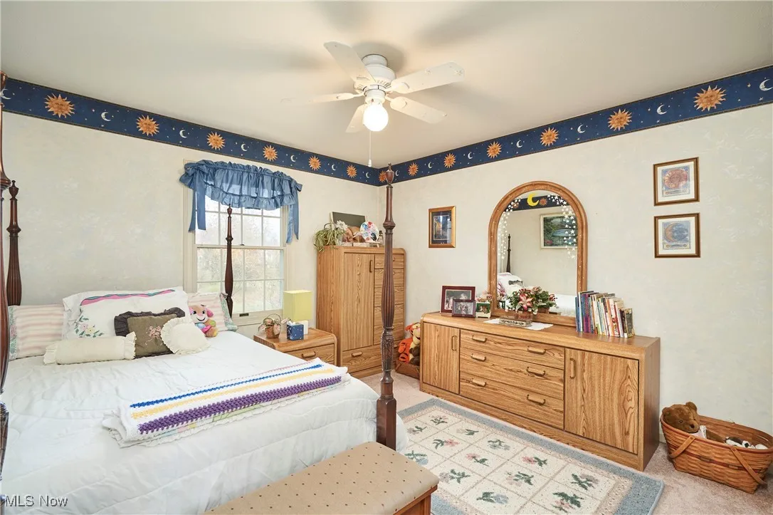 Bedroom with ceiling fan and light colored carpet