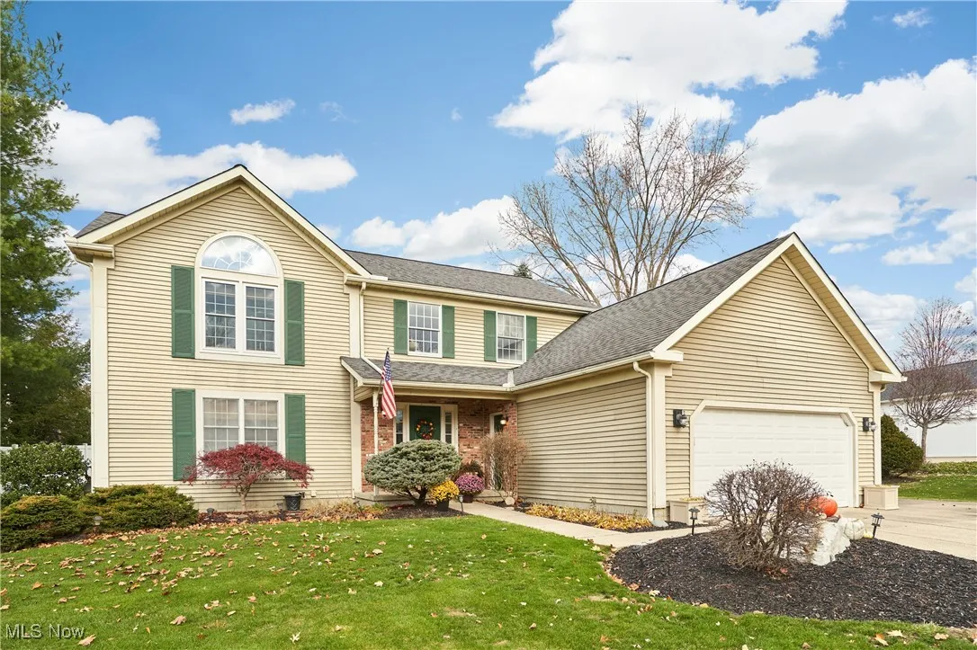 Traditional home with a porch, a front yard, roof with shingles, concrete driveway, and a garage